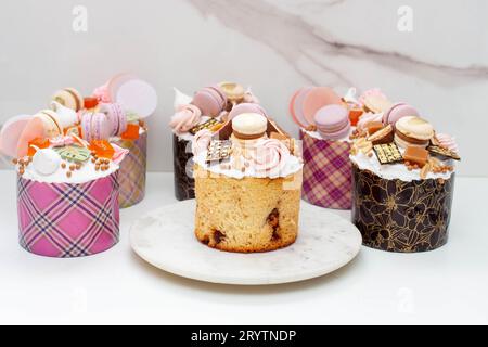 Orthodoxes osterbrot reich dekoriert mit Süßigkeiten, Makronen, Schokolade und essbaren Blüten mit gesalzener Karamellfüllung Stockfoto