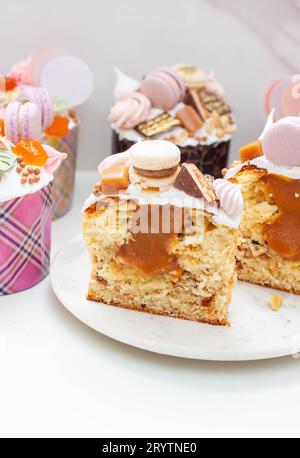 Orthodoxes osterbrot reich dekoriert mit Süßigkeiten, Makronen, Schokolade und essbaren Blüten mit gesalzener Karamellfüllung Stockfoto