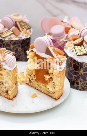 Orthodoxes osterbrot reich dekoriert mit Süßigkeiten, Makronen, Schokolade und essbaren Blüten mit gesalzener Karamellfüllung Stockfoto