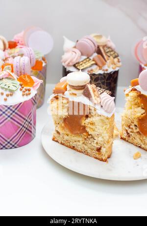 Orthodoxes osterbrot reich dekoriert mit Süßigkeiten, Makronen, Schokolade und essbaren Blüten mit gesalzener Karamellfüllung Stockfoto