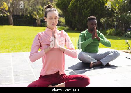 Verschiedene Paare üben Yoga und Meditieren im Garten Stockfoto