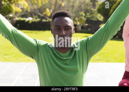 Porträt eines afroamerikanischen Mannes, der Yoga und Dehnübungen im Garten praktiziert Stockfoto