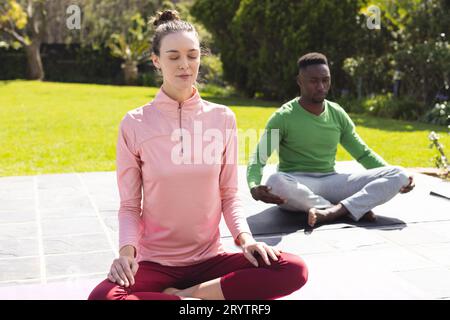 Verschiedene Paare üben Yoga und Meditieren im Garten Stockfoto