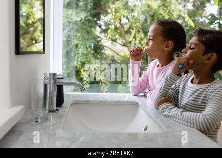 Birassische Geschwister im Pyjama, die morgens Zähne putzen, Kopierraum Stockfoto