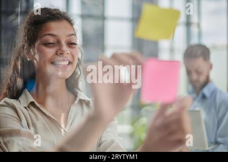 Ihre Vision zum Leben erwecken. Aufnahme einer selbstbewussten Geschäftsfrau, die ihrem Kollegen mit Haftnotizen an einer Glaswand im Büro eine Idee vorstellt. Stockfoto