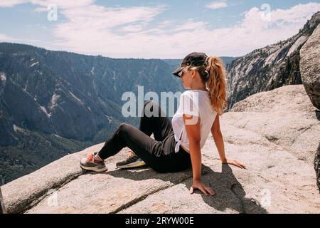 Eine junge blonde Frau, die auf einer felsigen Klippe in den Dolomiten in Kalifornien sitzt Stockfoto
