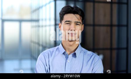 Nahaufnahme eines jungen asiatischen Geschäftsmanns, der in einem leeren Büro steht Stockfoto