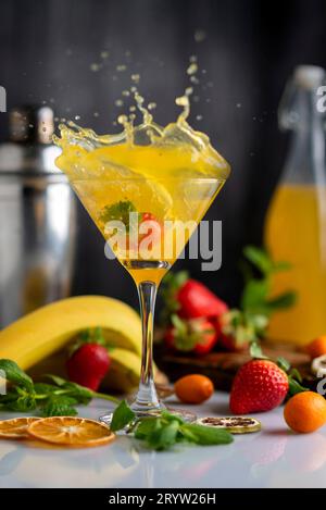 Ein vertikaler Schuss eines Cocktailglases mit Fruchtgetränk, Orangen-Erdbeeren, Bananen und Kumquats Stockfoto