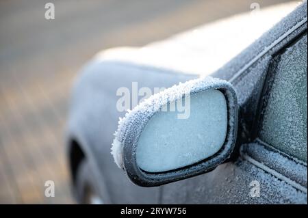 Ein Seitenspiegel eines Fahrzeugs ist mit Schnee bedeckt, ein weiterer Seitenspiegel im Hintergrund Stockfoto