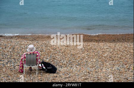 Seniorin, die sich an einem Kieselstrand entspannt. Sommerferien, Leute Freizeit Stockfoto