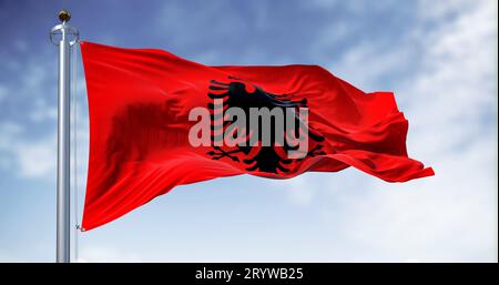 Albanische Nationalflagge, die an klaren Tagen im Wind wehte. Rote Flagge mit schwarzem zweiköpfigen Adler. Rendern der 3D-Darstellung. Flatternder Stoff. Stockfoto