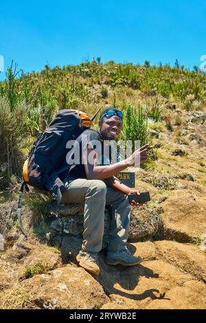 Ein dunkelhäutiger Kerl mit Rucksack ruht in den Bergen Stockfoto