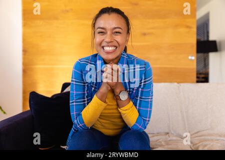 Glückliche birassische Frau, die Videoanrufe im Wohnzimmer macht Stockfoto