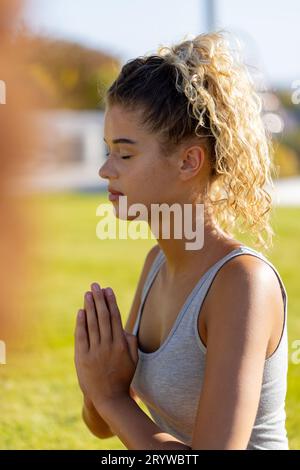 Birassische Frau, die auf Gras sitzt, Yoga macht und im Garten meditiert Stockfoto