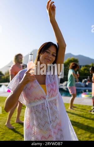 Porträt einer glücklichen, birassischen Frau, die mit ihren Freunden auf einer Party im Garten tanzt Stockfoto