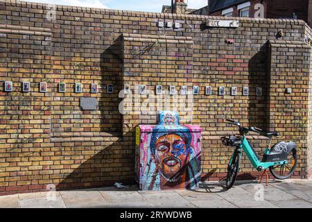 Ein Tier-Leihfahrrad vor einer Wand und Street Art in Brick Lane, London, E1. Stockfoto