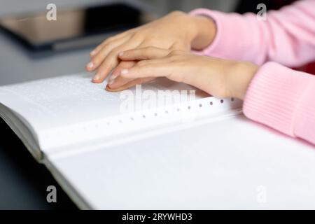 Hände eines blinden, birassischen Schulmädchens am Schreibtisch mit brailleschrift im Unterricht mit Kopierraum Stockfoto