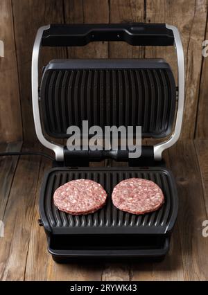 Rindfleisch-Patties für einen Burger werden auf einem intelligenten elektrischen Grill gebraten. Hausgemachte Hamburger kochen. Zutaten für Burger. Stockfoto