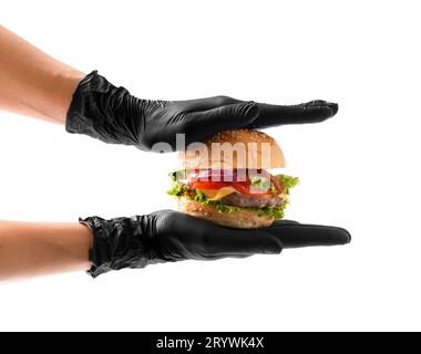 Hände in schwarzen Handschuhen halten einen saftigen, appetitlichen Rindfleischburger auf weißem Hintergrund. Hamburger in Händen isoliert. Banner, Fast-Food-Werbung. Stockfoto