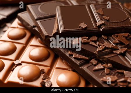 Verschiedene Schokoladensorten. Schwarz, Milchschokolade, ganze Tiegel, Stücke, Schokoladenchips aus der Nähe. Schokoladenhintergrund. Stockfoto