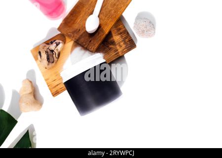 Modell eines Kunststoffbehälters für Kollagenpulver. Löffel mit Kollagen auf Holzbühnen, Glasbecher und Monstera-Blatt Stockfoto