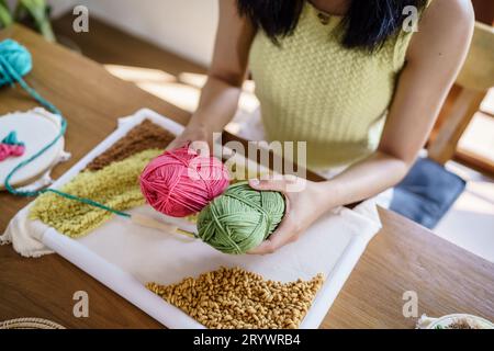 Stanznadel. Asiatische Frau, die handgemachtes Hobby-Stricken in der Atelierwerkstatt herstellt. Designer-Arbeitsplatz Handgefertigtes Bastelprojekt DIY Embro Stockfoto