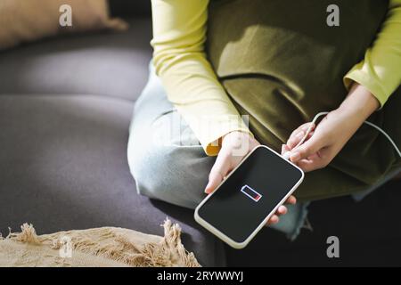 Frauenhände Laden der Mobiltelefonbatterie mit niedrigem Akkuladestand. Anschließen eines Ladegeräts an ein Smartphone Â mit Powerbank-Stromversorgung Stockfoto