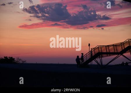 Schatten von zwei Personen und die Aussichtsplattform Tetraeder Bottrop in Bottrop bei Sonnenuntergang Stockfoto