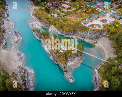 Das Luftbild der orthodoxen Kirche Patmos auf der kleinen Insel mit der Brücke über den malerischen Fluss Katun in den Altai-Bergen in Russland. Stockfoto