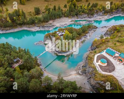 Das Luftbild der orthodoxen Kirche Patmos auf der kleinen Insel mit der Brücke über den malerischen Fluss Katun in den Altai-Bergen in Russland. Stockfoto