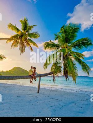 Praslin Seychellen tropische Insel mit Stränden und Palmen, Paar Männer und Frauen in Hängematte schwingen am Strand unter einem Stockfoto