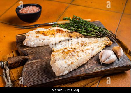 Rotes Meerbarschfilet, Rotbarsch auf Holzbrett. Orangefarbener Hintergrund. Draufsicht. Stockfoto