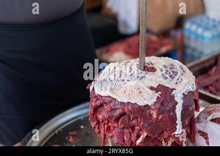 Der Meister bereitet türkischen Kebab zu, um aus rotem Fleisch, ungekochtem Dönerfleisch, griechischen Gyros am Spieß in einem Restaurant zu kochen . Hochwertige Fotos Stockfoto