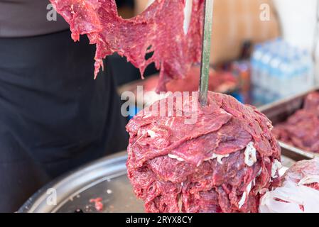 Der Meister bereitet türkischen Kebab zu, um aus rotem Fleisch, ungekochtem Dönerfleisch, griechischen Gyros am Spieß in einem Restaurant zu kochen . Hochwertige Fotos Stockfoto