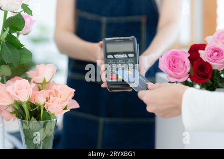 Abgeschnittene Aufnahme einer Floristin, die dem Kunden eine Kreditkarte gibt Stockfoto