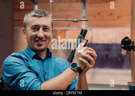 Ein Mann übt das Schießen mit einer Pistole auf einem Schießstand, während er schützende Kopfhörer trägt Stockfoto