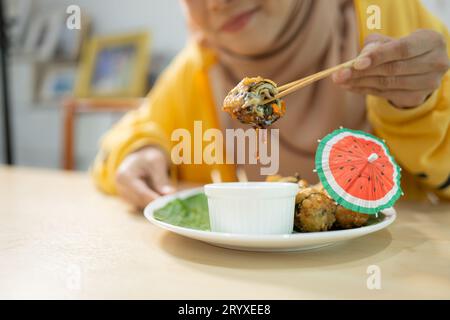 Muslimisches Mädchen isst Pilz-Sushi im Restaurant. Selektiver Fokus auf Sushi Stockfoto