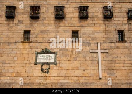 In den Straßen von Santiago de Compostela. Die Fassade des großen Benediktinerklosters San Pelayo mit einem riesigen Kreuz und einer Gedenktafel für Freiheitskämpfer während der Napoleonischen Kriege. Gebäude mehrerer Klöster umgeben die berühmte Kathedrale, das letzte Ziel aller Pilger auf dem Weg von St. James oder Jakobsweg Stockfoto