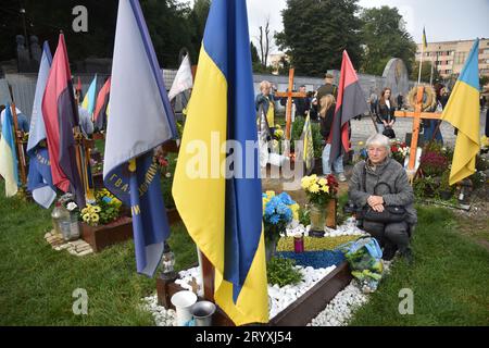 Lviv, Ukraine. Oktober 2023. Eine Frau sitzt in der Nähe des Grabes eines ukrainischen Soldaten, der während des russisch-ukrainischen Krieges auf dem Lychakiv-Friedhof in Lemberg am Tag des Verteidigers der Ukraine getötet wurde. Quelle: SOPA Images Limited/Alamy Live News Stockfoto