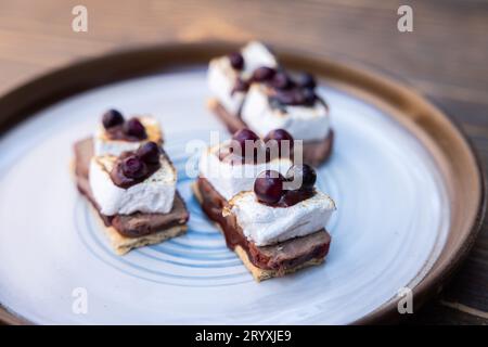 Köstliche Huckleberry-Rindfleischgeschäfte mit gerösteten Marshmallows mit geschmolzener Schokolade und einer Huckleberry-Sauce im Freien Stockfoto