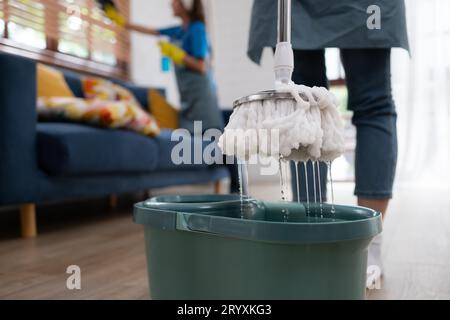 Nahaufnahme von Mopp und Eimer mit Reinigungsprodukten im Wohnzimmer Stockfoto