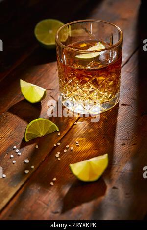 Sommergetränk, Whiskey, Tequila oder Cognac, Limonade, alkoholischer oder alkoholfreier Cocktail mit Limetten und Salz auf einem Holztisch Stockfoto