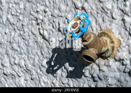 Nahaufnahme eines Wasserhahns im Freien an einer strukturierten Wand Stockfoto