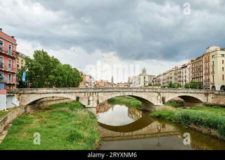 Farbenfrohe gelbe und orangene Häuser und Brücke Pont de Sant Agusti spiegeln sich im Fluss Onyar in Girona, Katalonien, Spanien. Ch Stockfoto