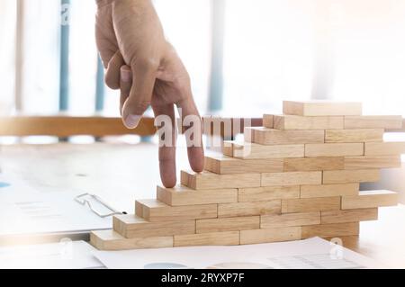 Erfolgskonzept mit Geschäftsfrau, die Holzblocktreppen mit der Hand klettert im Business Concept Stockfoto