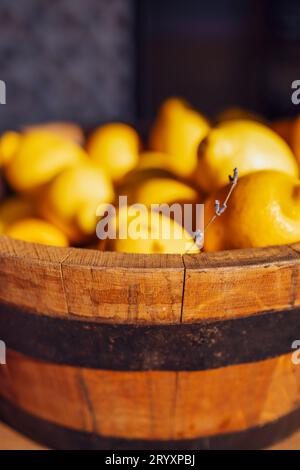 Extrime Nahaufnahme einer vertikalen Ansicht eines Holzeimers voller frischer Zitronen und Lavendelzweig. Stockfoto