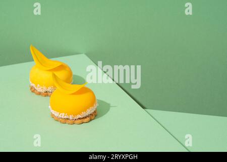 Ein Tablett mit frisch gebackenen gelben Cupcakes mit köstlichem weißem Schlagseißguss auf grünem Hintergrund Stockfoto