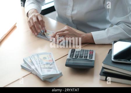 Geschäftsfrau analysiert Investitionstabellen und drückt Rechnertasten über Dokumente. Buchungskonzept. Stockfoto