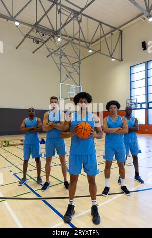 Porträt von verschiedenen männlichen Basketballspielern, die blaue Sportkleidung im Fitnessstudio tragen, Kopierraum Stockfoto