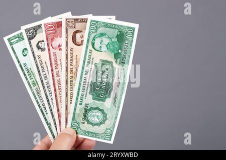 Alte paraguayische Moneyi in der Hand auf grauem Hintergrund Stockfoto